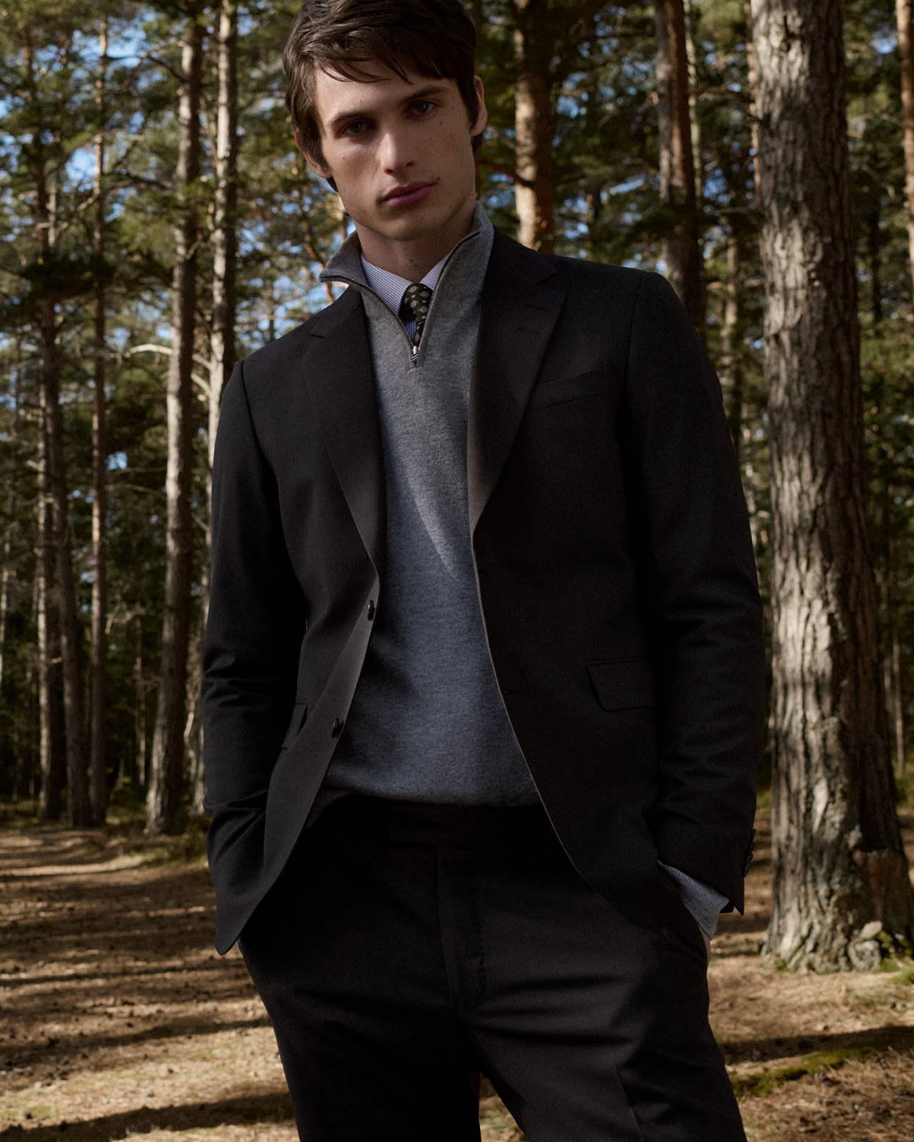 Man in a with shirt, light grey knit and a navy blazer